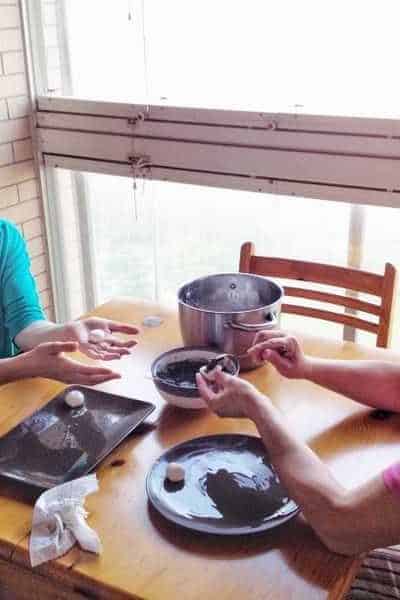 Two women rolling a Chinese treat together.