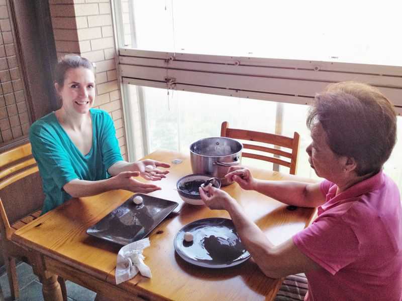 Two women rolling a Chinese treat together.