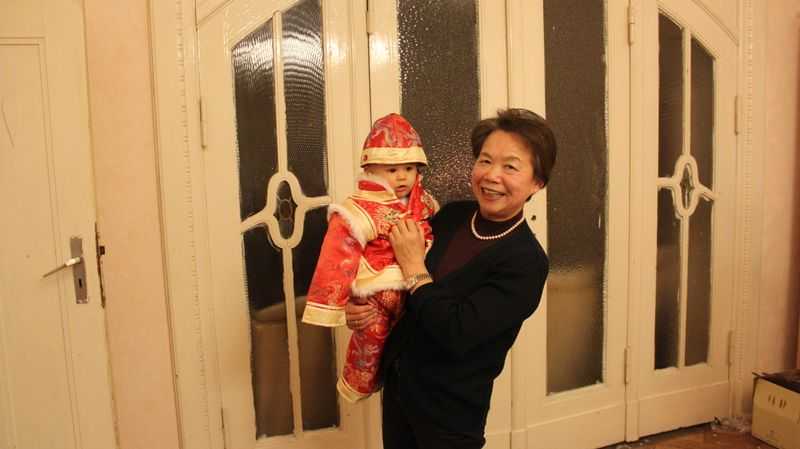A grandmother holding her grandson in a red Chinese suit