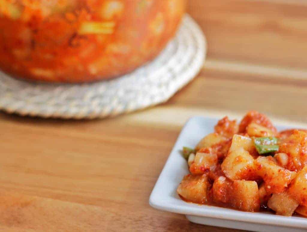 A plate and a jar of radish kimchi on a table