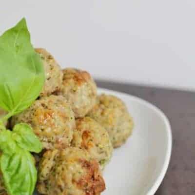 A pile of baked meatballs with some basil