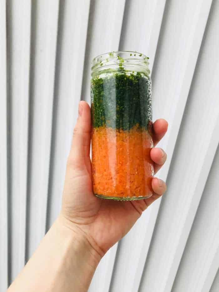 A glass jar filled with shredded kale and carrots