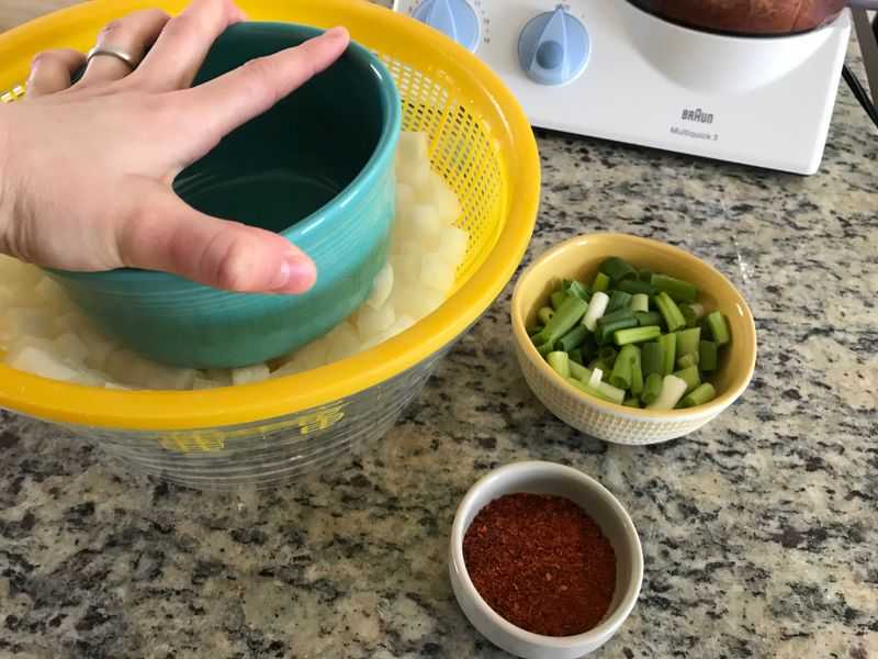 Pressing a blue bowl down on top of cubed daikon