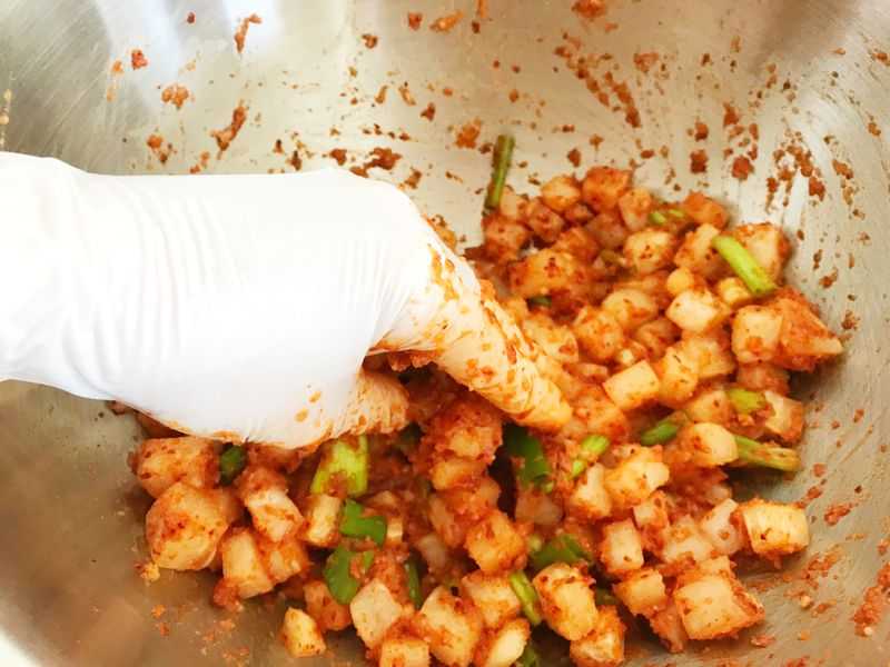 Mixing spicy kimchi with a gloved hand