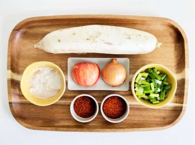 Radish kimchi ingredients arranged on a wood platter