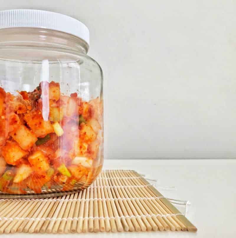 A jar of kimchi sitting on a bamboo mat