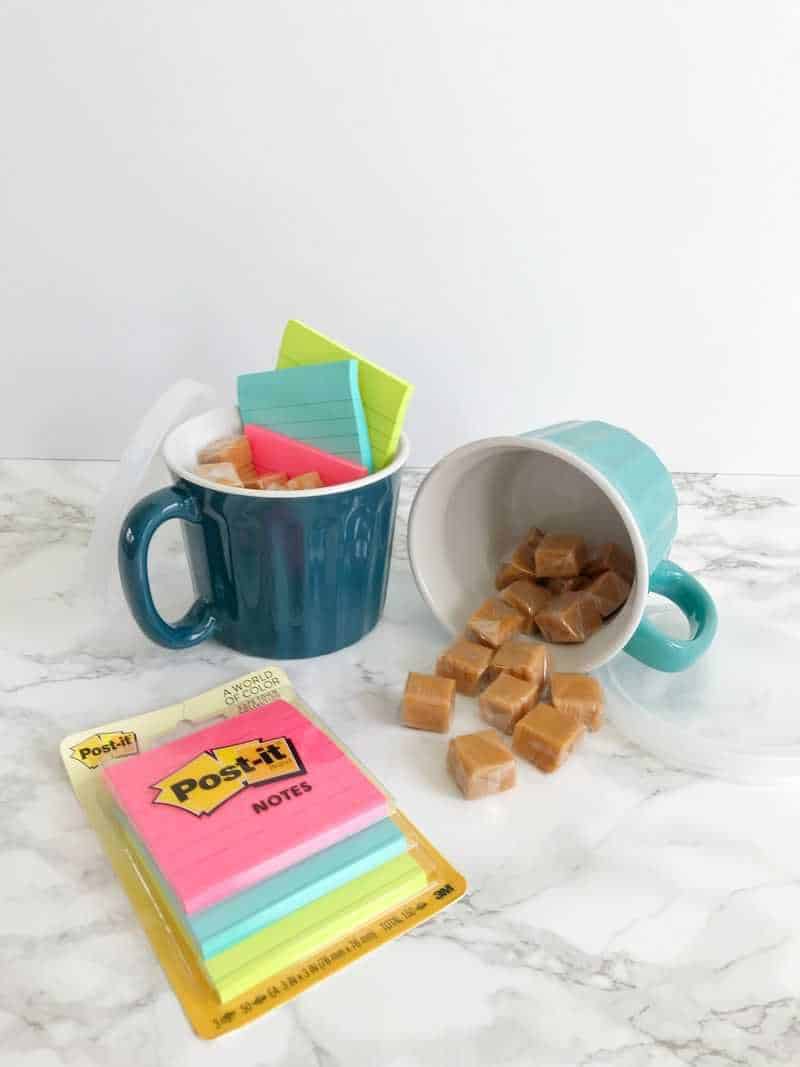 Two mugs spilling over with candy and Post-its
