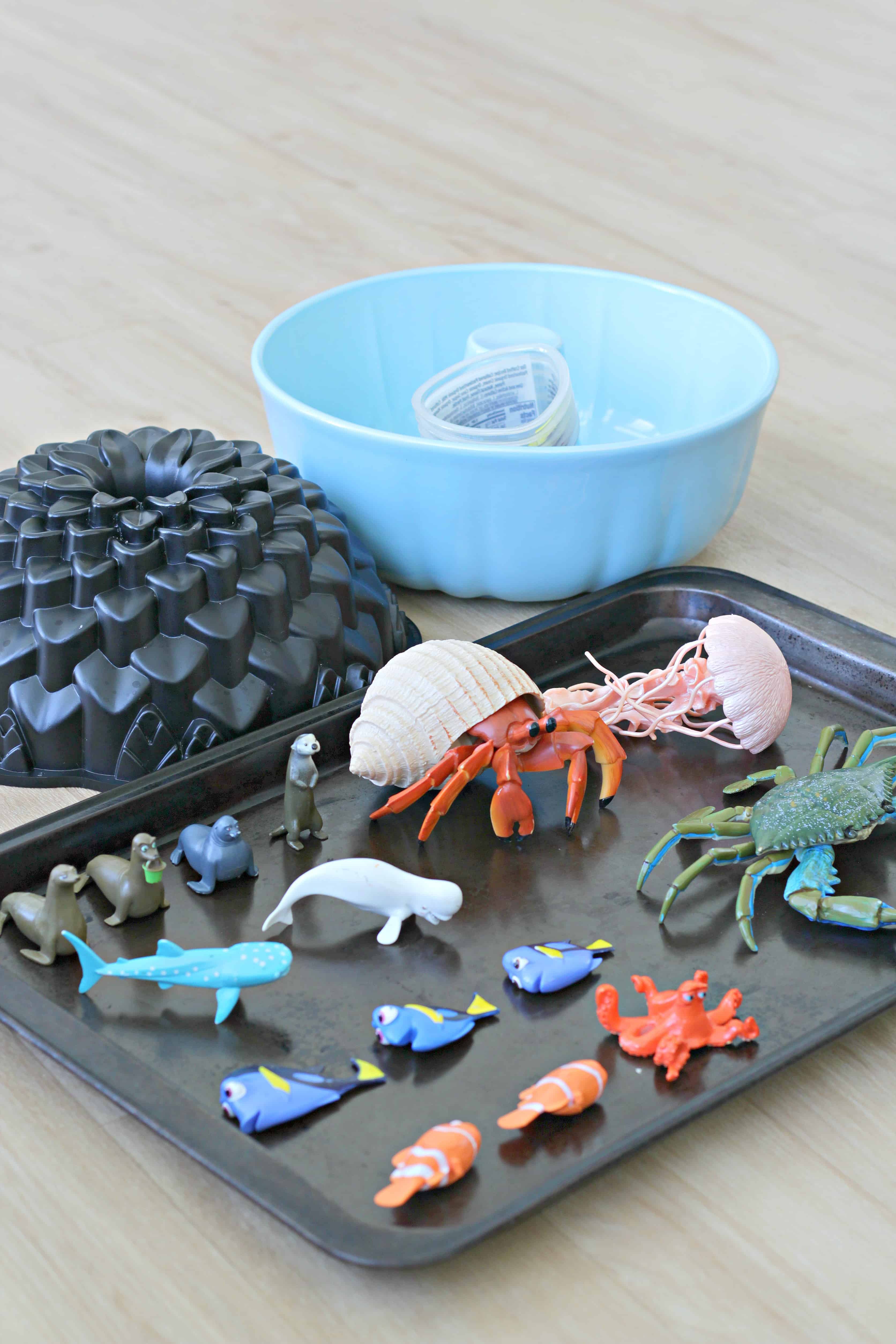 Plastic sea creatures on a pan with cake pans beside them