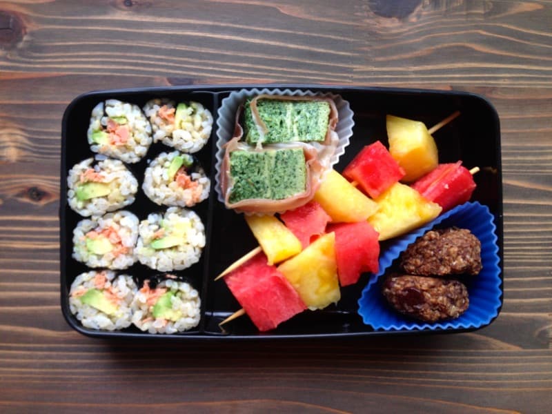 Healthy lunch box with sushi and fruit