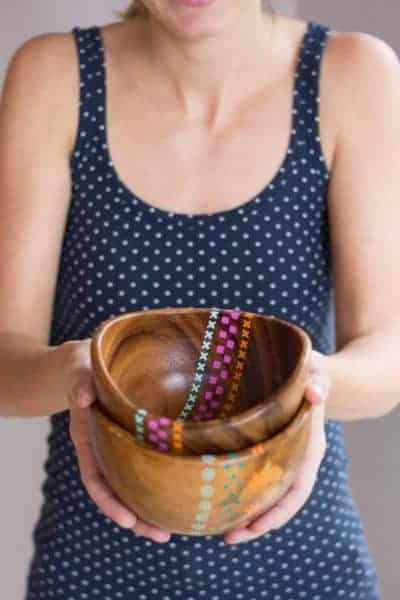 A woman holding a wood bowl with painted patterns