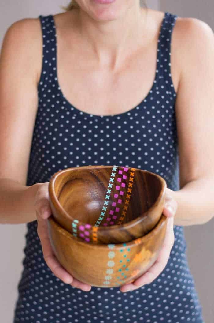 A woman holding a wood bowl with painted patterns