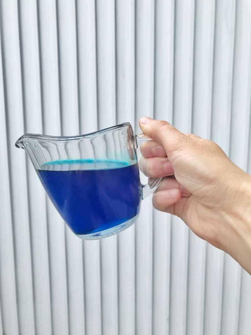 Blue simple syrup being help by a woman