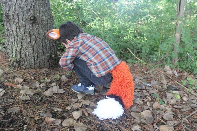 Boy with yarn fox tail in the woods