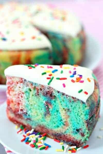 A slice of jello poke cake on a plate with sprinkles