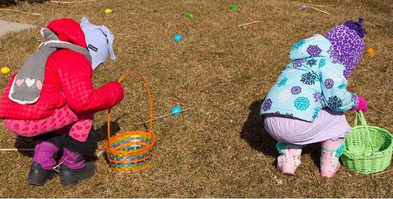 Two children playing Easter game hunting eggs