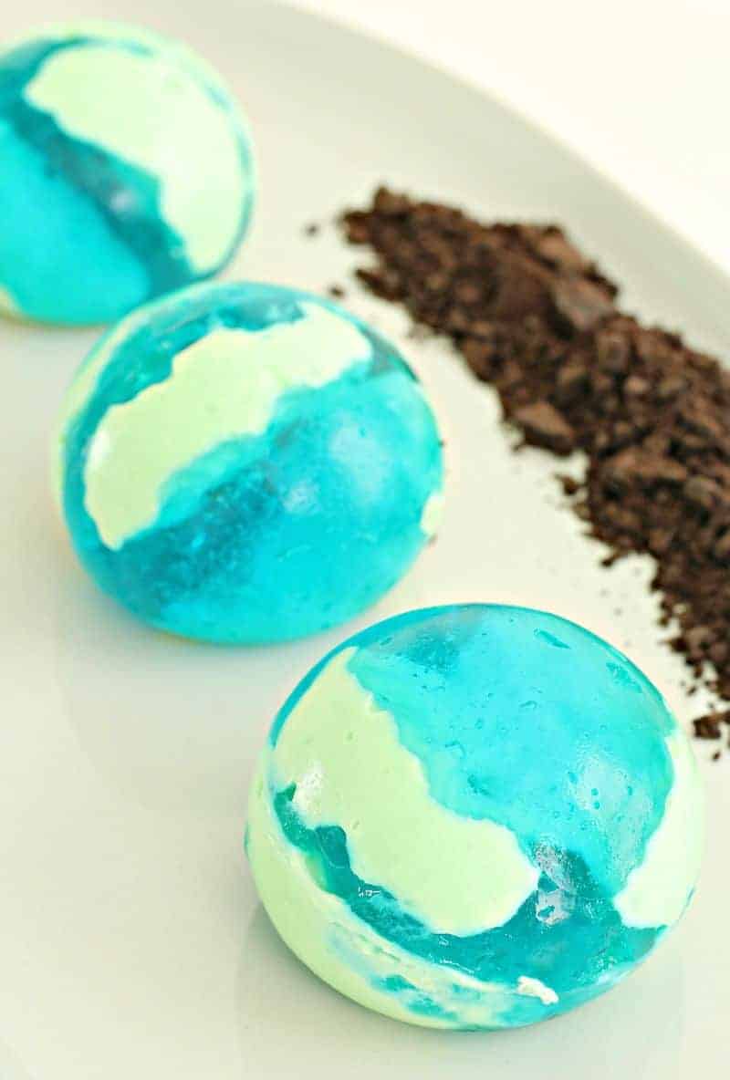 Three green and blue Jello balls on a plate