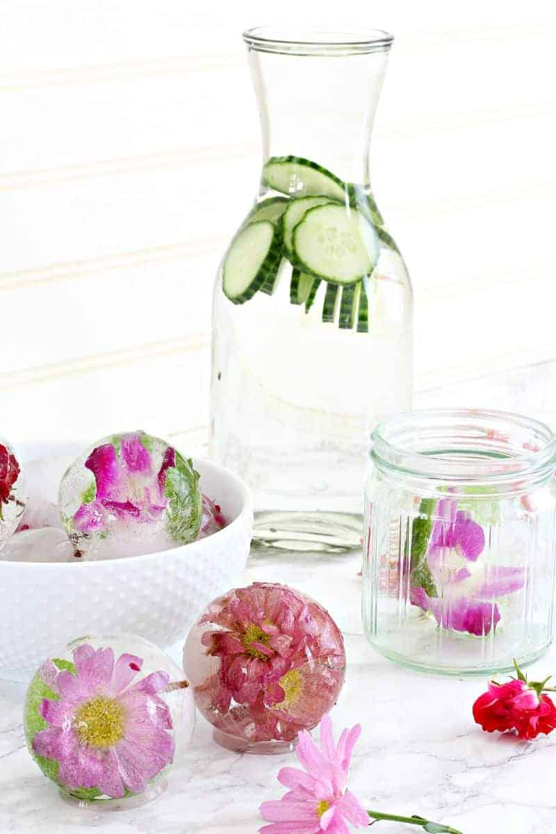 Flowers in ice next to a carafe of cucumber water