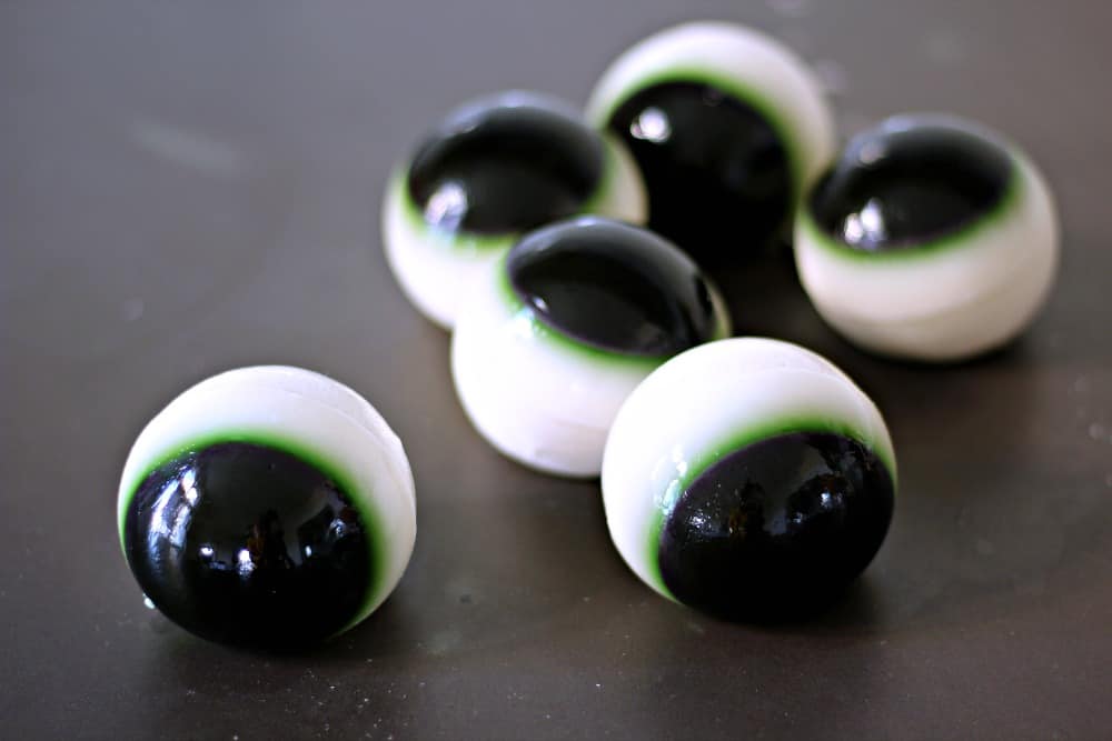 Jello eyeball shots on a black counter.