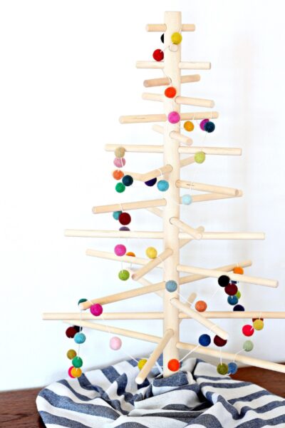 A wooden dowel tree decorated with a colorful felt ball garland