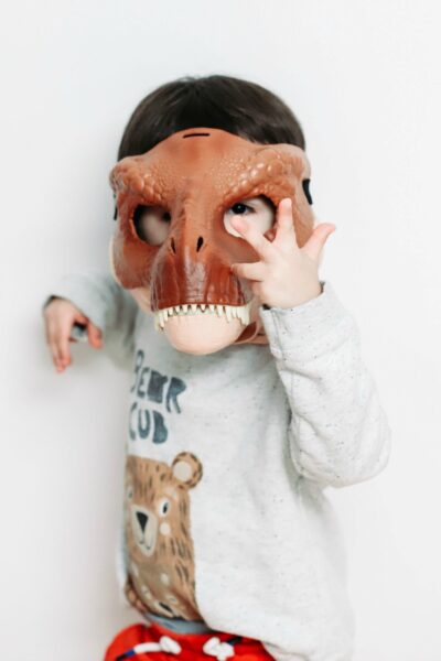 A minimalist boy wearing a dinosaur mask
