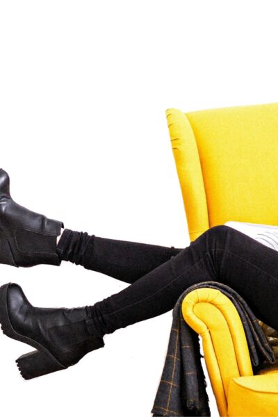 A woman in black pants making money from home on a yellow couch