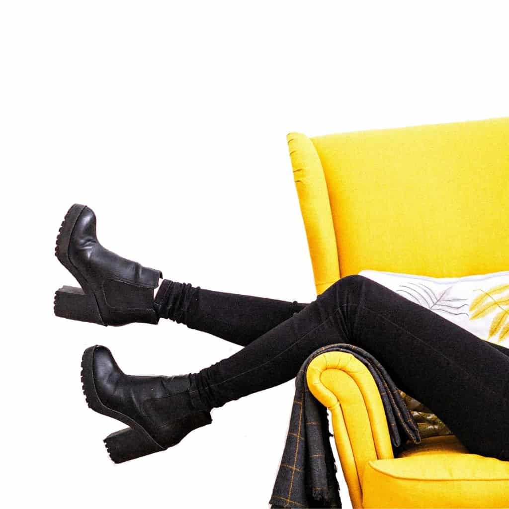 A woman in black pants making money from home on a yellow couch