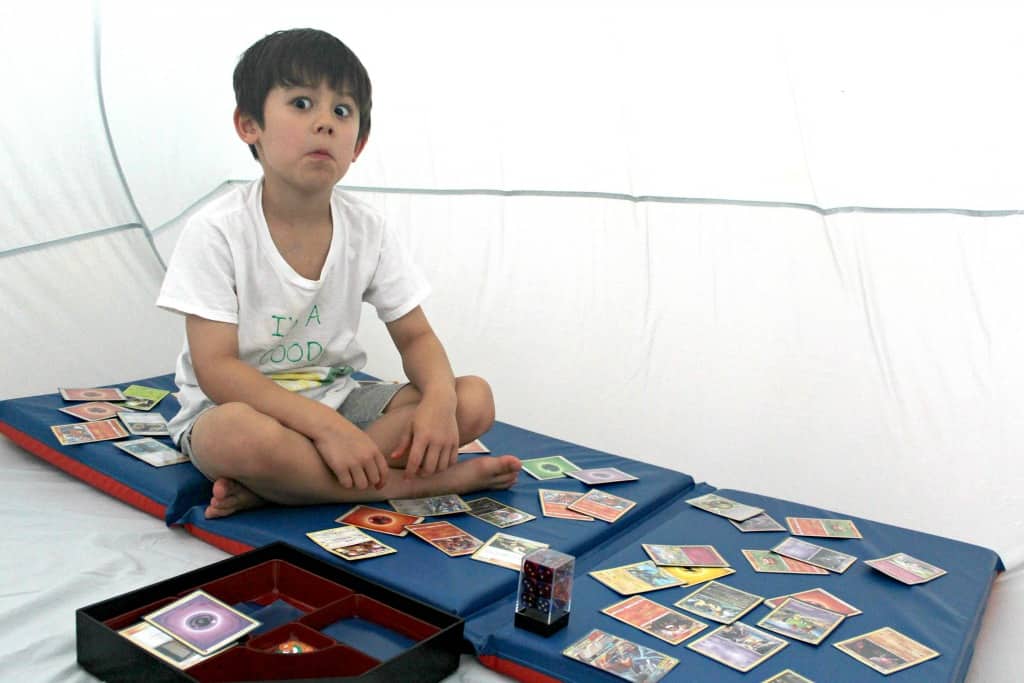 A boy playing with cards inside an air tent.