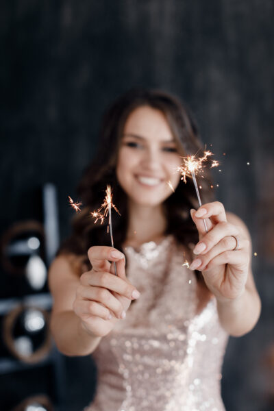 A woman with sparklers reciting New Year's quotes at a party