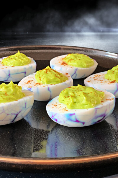 Halloween deviled eggs on a black plate at a Halloween party