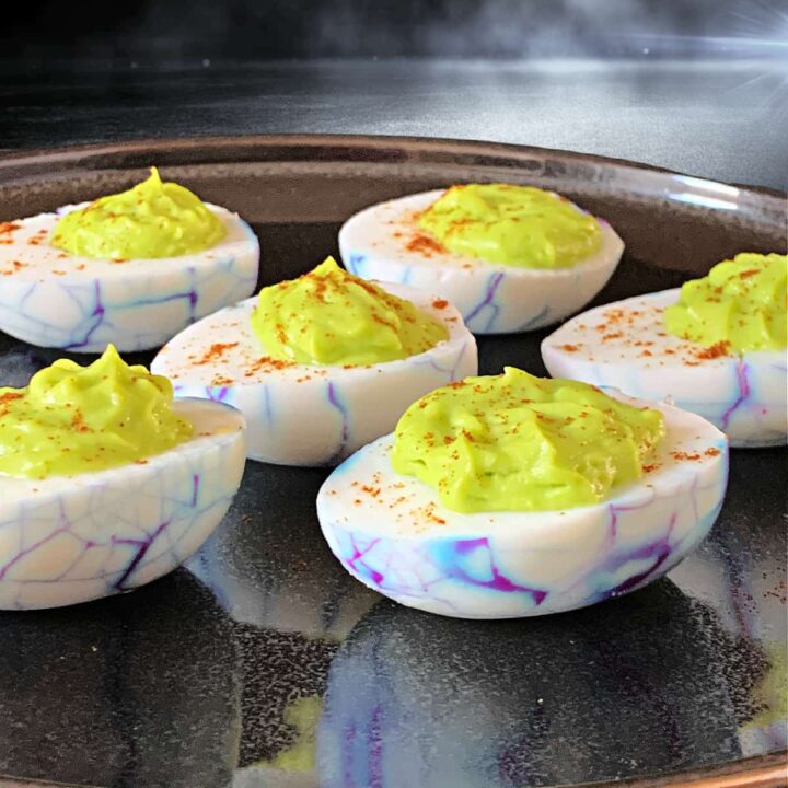 Halloween deviled eggs on a black plate at a Halloween party